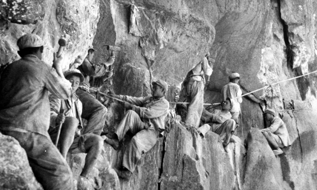 1954年，修筑康藏公路的解放軍戰(zhàn)士們?cè)谂瓋砂兜膽已露副谏媳偕街?。新華社稿 李萬(wàn)春、張加里攝